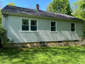 Power washing Uxbridge – Back exterior wall of a house with visible dirt and mildew on the lower siding, ideal for pressure cleaning services.