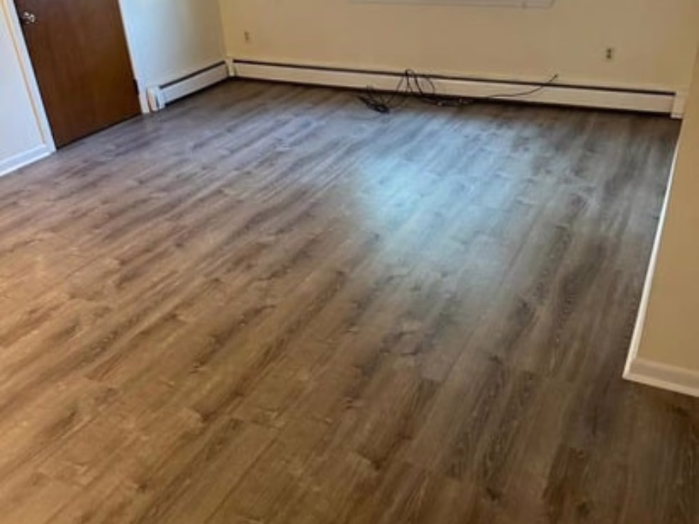 Vinyl flooring installation in Milford showcasing a modern wood-look finish in a clean, empty room.