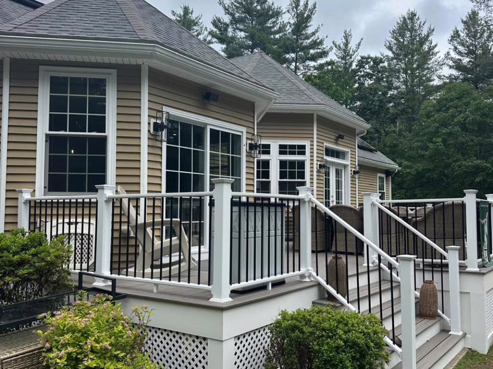 Deck renovation in Norfolk MA featuring a modern composite deck with white and black railings, upgraded stairs, and outdoor seating area.