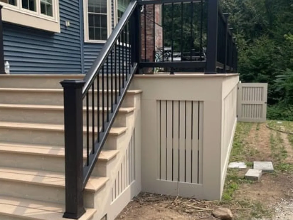 Side view of deck renovation showing stairs, railing, and under-deck storage door.