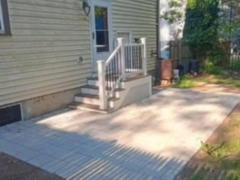 New deck and patio installation in Bellingham, MA, showcasing modern stone pavers and railings