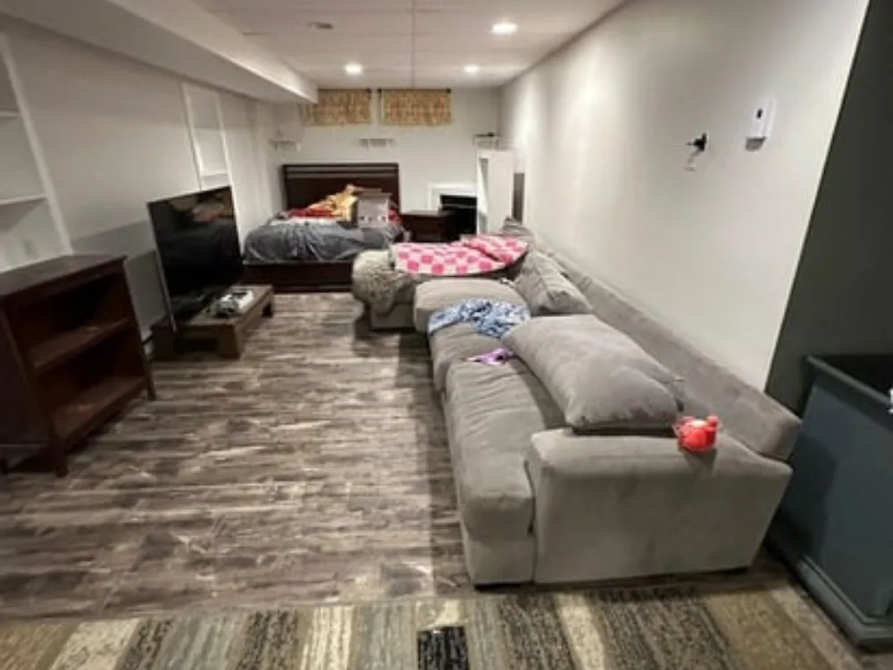 Comprehensive view of a finished basement bedroom and lounge in a Grafton MA basement remodeling.