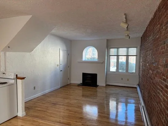 Living area featuring a modern industrial apartment remodel with exposed brick and a decorative fireplace.