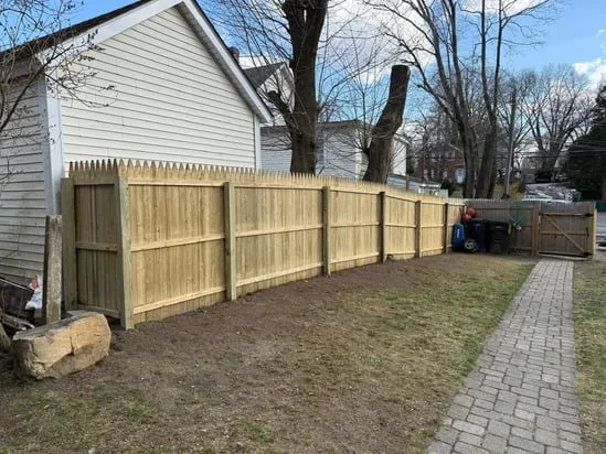 Completed wood fence replacement in North Kingstown showing property gate.