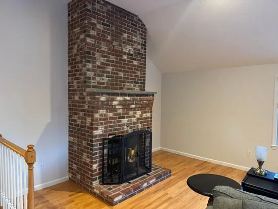 The finished result of interior painting in Milford, CT, emphasizing the clean contrast between the new wall color and a classic brick fireplace.