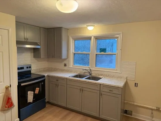 Completed kitchen remodeling transformation featuring gray cabinets and new appliances.